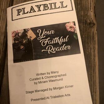  A white playbill lies on a wooden table. At top, center, is the word PLAYBILL in black and white block lettering. Underneath is the title “Your Faithful Reader” in italicized white script against a charcoal background with light pink flowers. In the bottom third of the page is simple black text that reads “Written by many Curated and Choreographed by Miriam Wasmund/Stage Managed by Morgan Kimer/Presented by Triskelion Arts.”